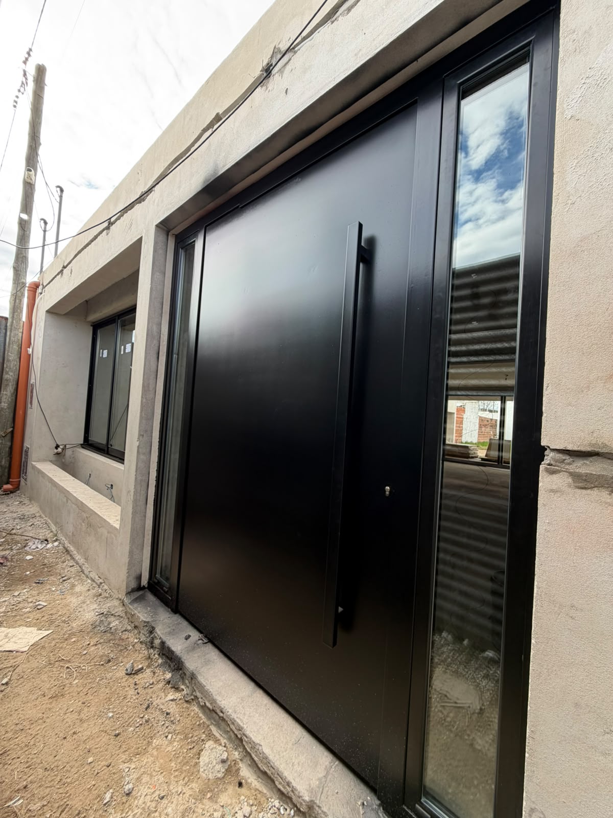 Puerta metálica negra instalada en una vivienda en obra